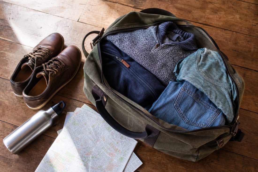 A packed weekend travel bag with layered clothing and closed shoes