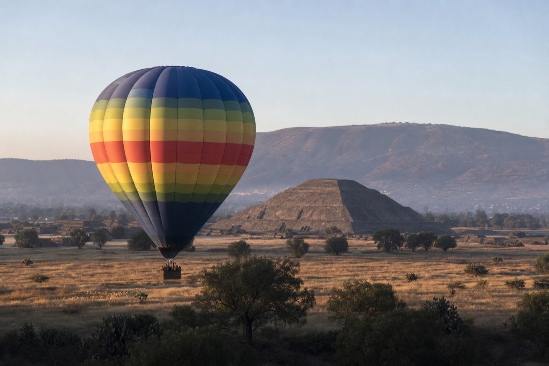 A hot air balloon drifting beside the Teotihuacan archaeological zone at first light