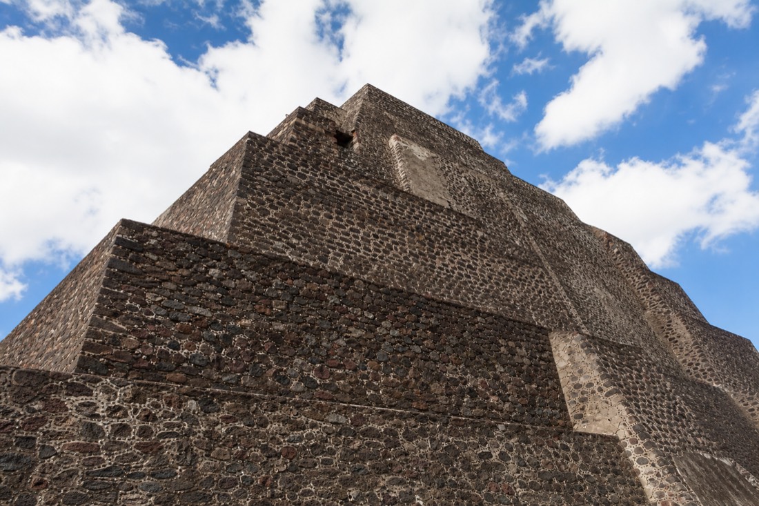 A large stepped stone pyramid photographed from below at a dramatic angle