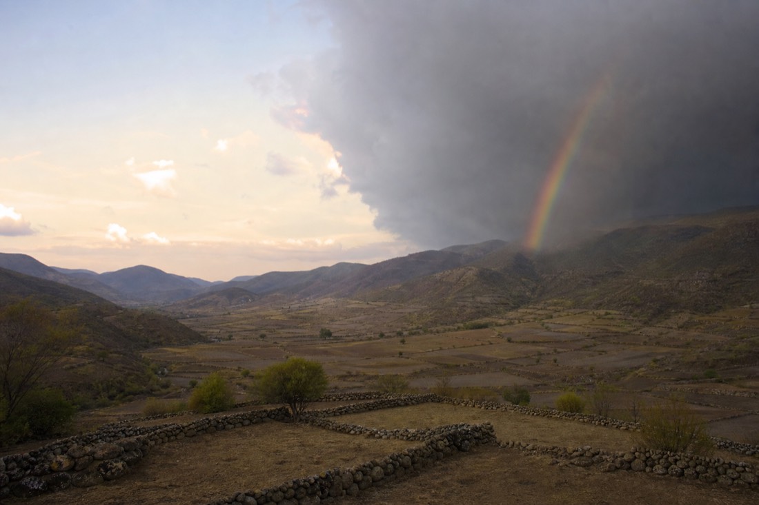 A highland valley split between clear dry-season sky and departing rain cloud