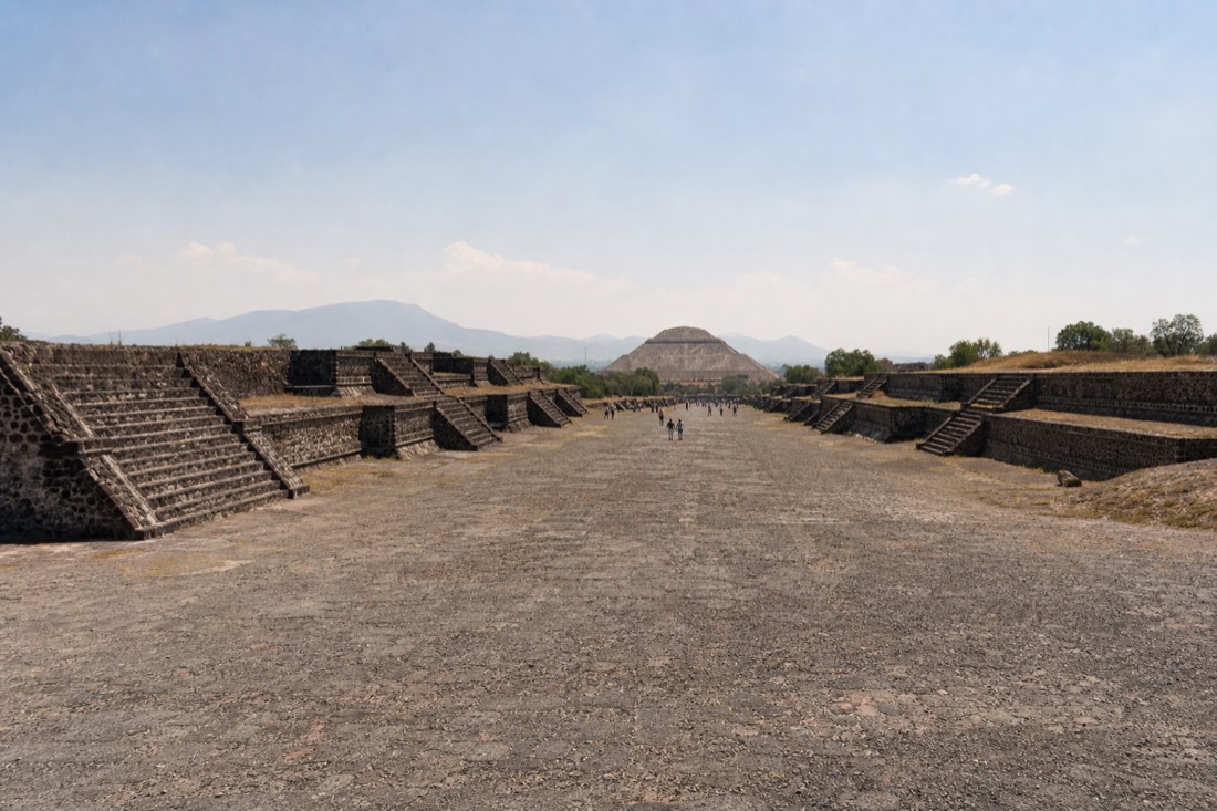Small distant figures walking the Avenue of the Dead at midday