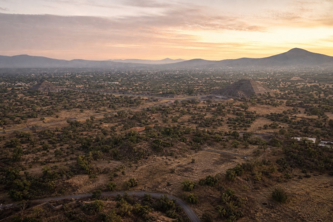 A wide panoramic view of the Teotihuacan valley at dawn with both pyramids visible