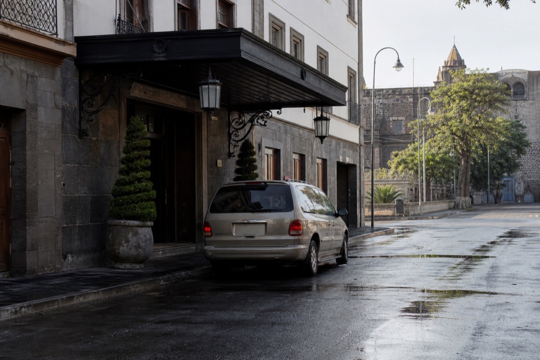 A Mexico City street corner with a minivan pulled over in early morning light
