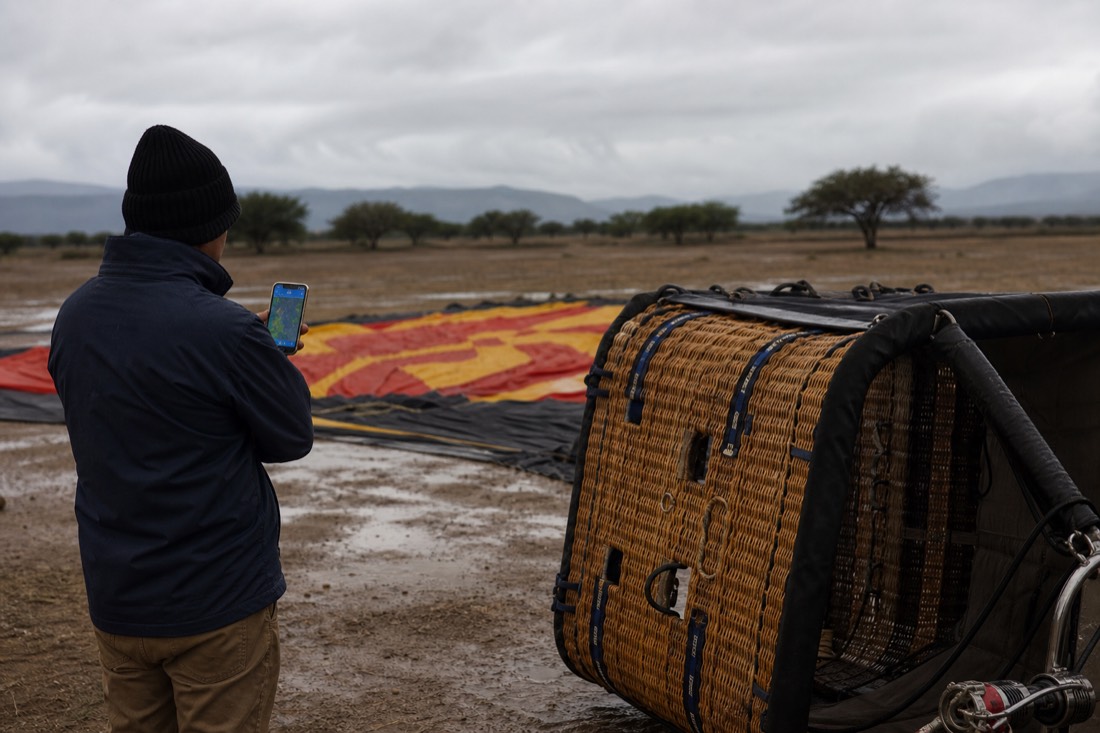 A ground crew waiting beside a grounded balloon under low grey cloud