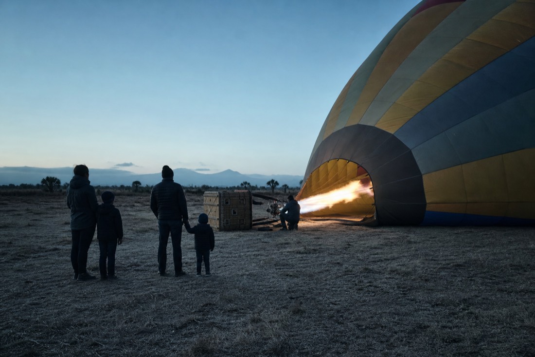 A family with children of different ages standing on a dawn launch field